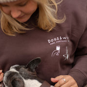 Person wearing a sweatshirt with 'DOGS & WINE' text and graphic, holding a dog.